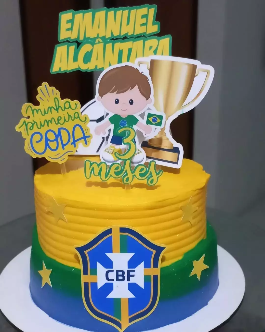 Bolo de aniversário com tema futebol e nome Emanuel Alcântara, decorado com taça e escudo da CBF